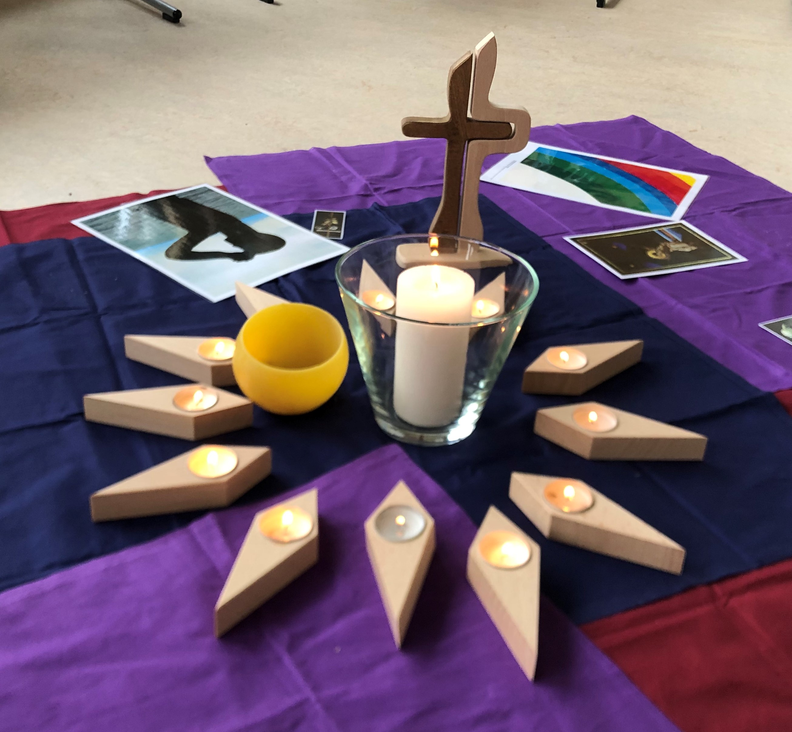 Kreis aus Kerzen vor einem Holzkreuz